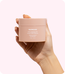 Glowlixir super hydrating mask in a woman's hand with a fresh and hydrated face in the background